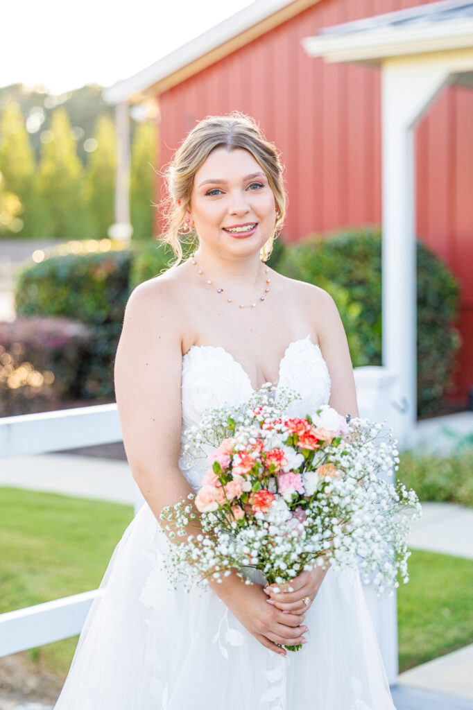 Bride in a white lace wedding gown holding a pastel bouquet at Carrollock Farms, a rustic barn wedding venue near Raleigh, North Carolina