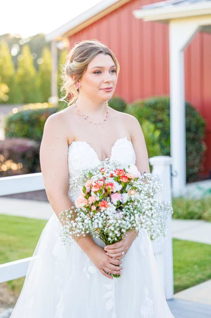 Bride in a white lace wedding gown holding a pastel bouquet at Carrollock Farms, a rustic barn wedding venue near Raleigh, North Carolina