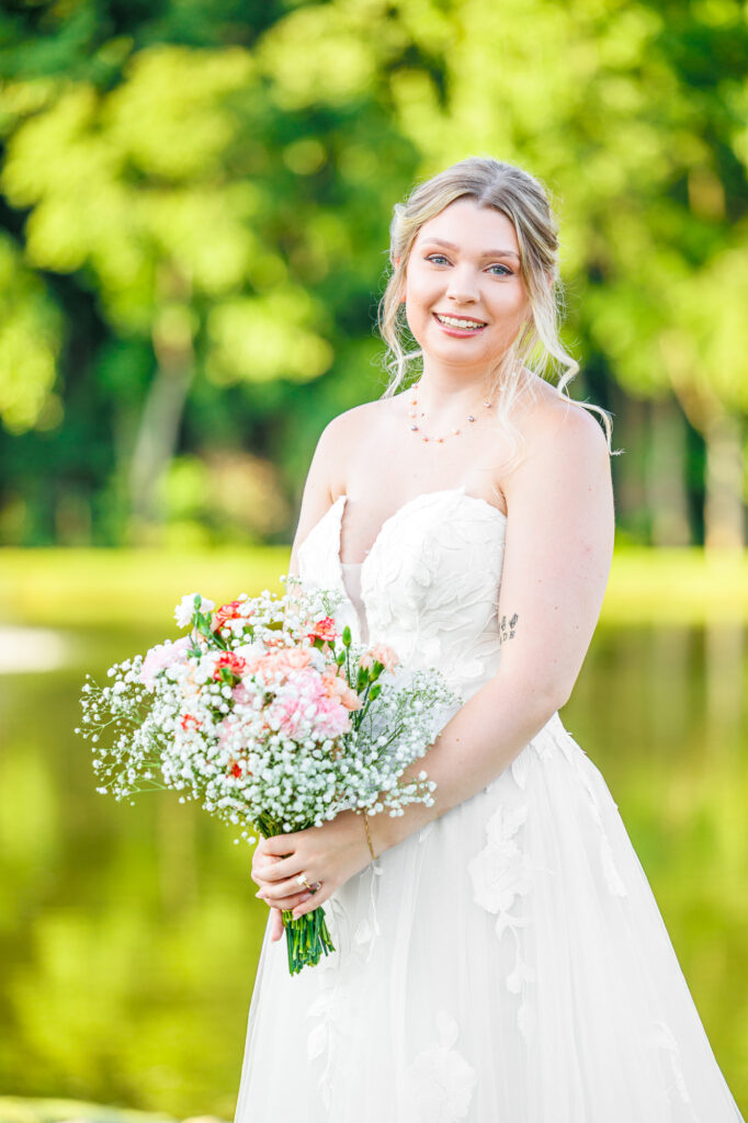Bride in a white lace wedding gown holding a pastel bouquet at Carrollock Farms, a rustic barn wedding venue near Raleigh, North Carolina