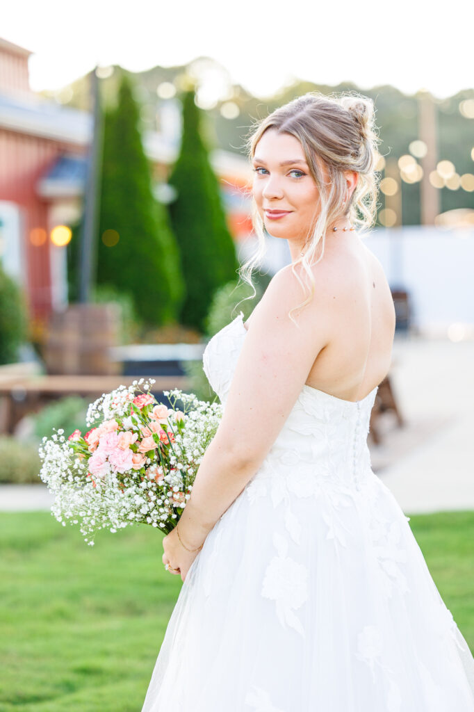 Bride in a white lace wedding gown holding a pastel bouquet at Carrollock Farms, a rustic barn wedding venue near Raleigh, North Carolina