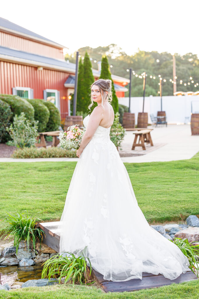 Bride in a white lace wedding gown holding a pastel bouquet at Carrollock Farms, a rustic barn wedding venue near Raleigh, North Carolina