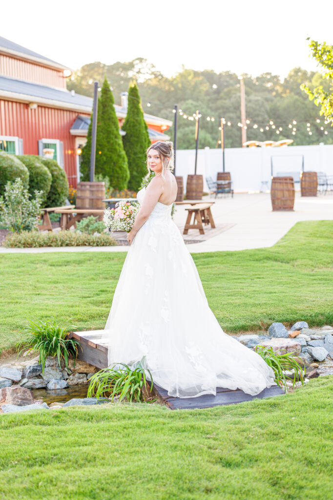 Bride in a white lace wedding gown holding a pastel bouquet at Carrollock Farms, a rustic barn wedding venue near Raleigh, North Carolina