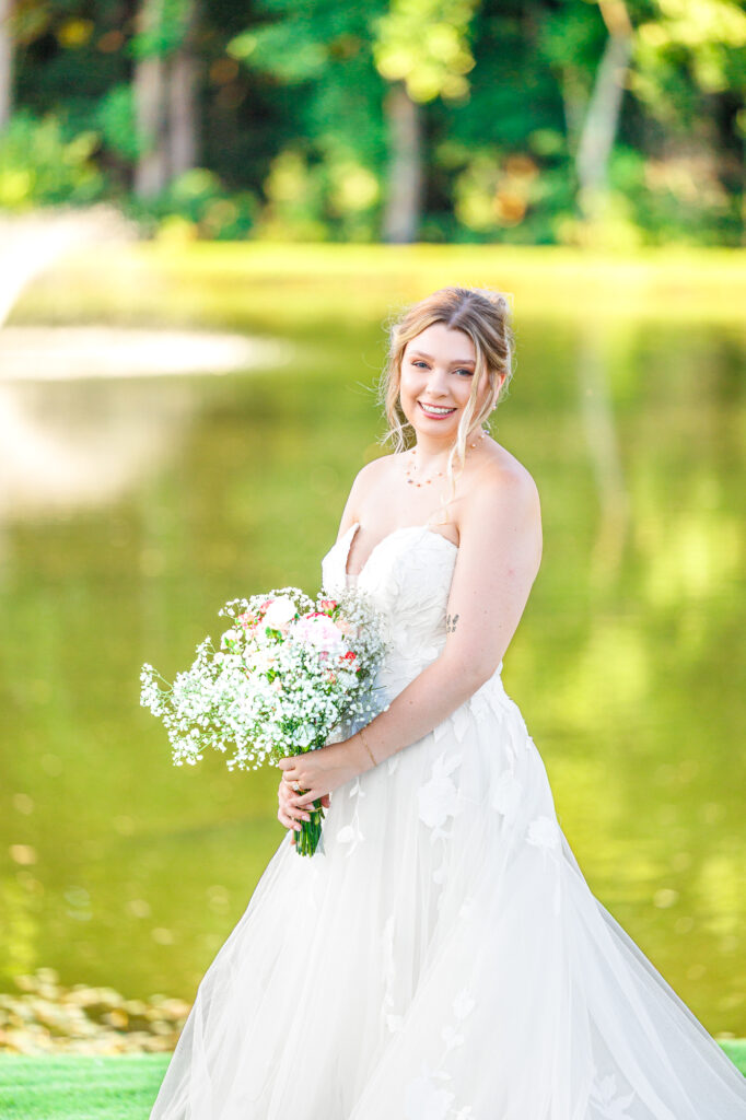 Bride in a white lace wedding gown holding a pastel bouquet at Carrollock Farms, a rustic barn wedding venue near Raleigh, North Carolina