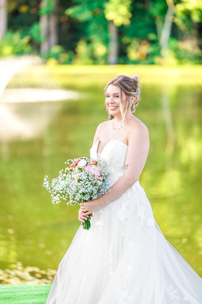Bride in a white lace wedding gown holding a pastel bouquet at Carrollock Farms, a rustic barn wedding venue near Raleigh, North Carolina