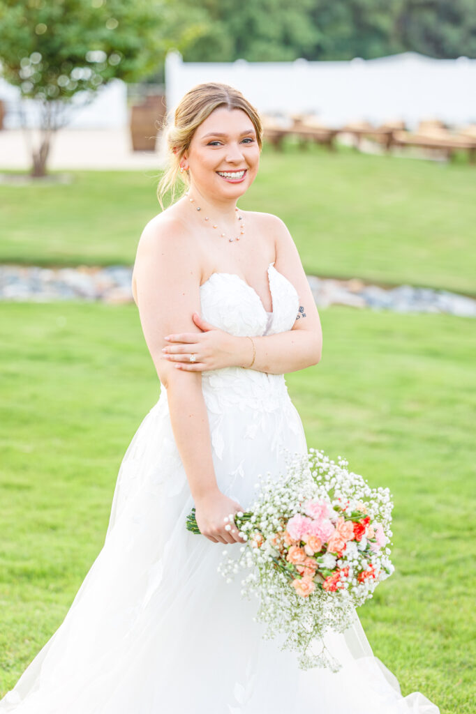 Bride in a white lace wedding gown holding a pastel bouquet at Carrollock Farms, a rustic barn wedding venue near Raleigh, North Carolina